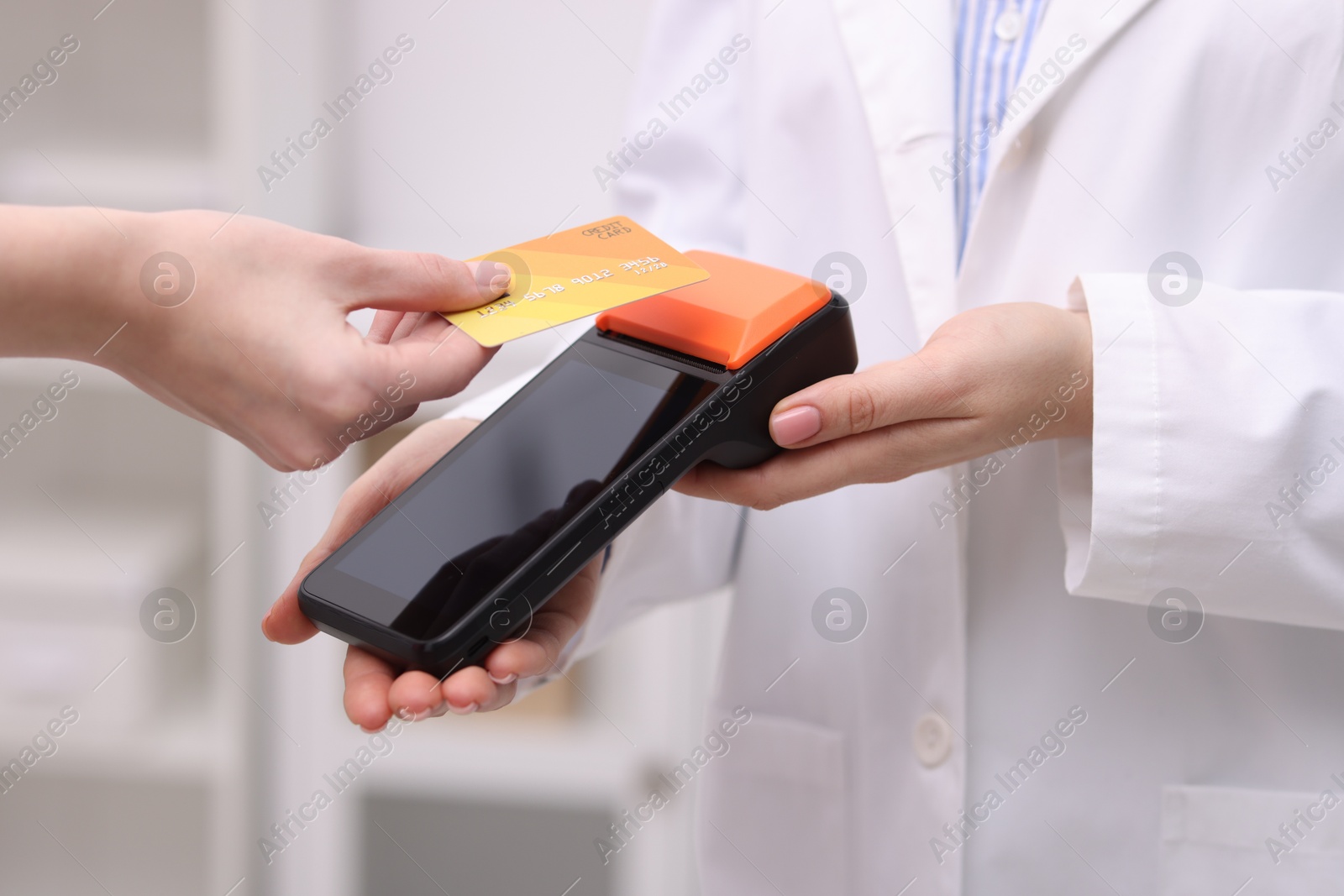 Photo of Woman paying with credit card via terminal against blurred background, closeup