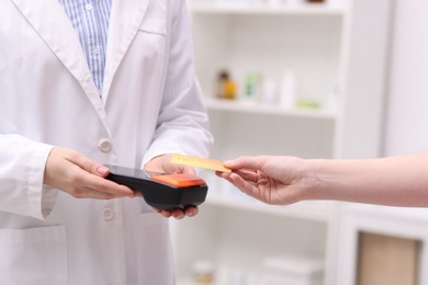 Photo of Woman paying with credit card via terminal against blurred background, closeup