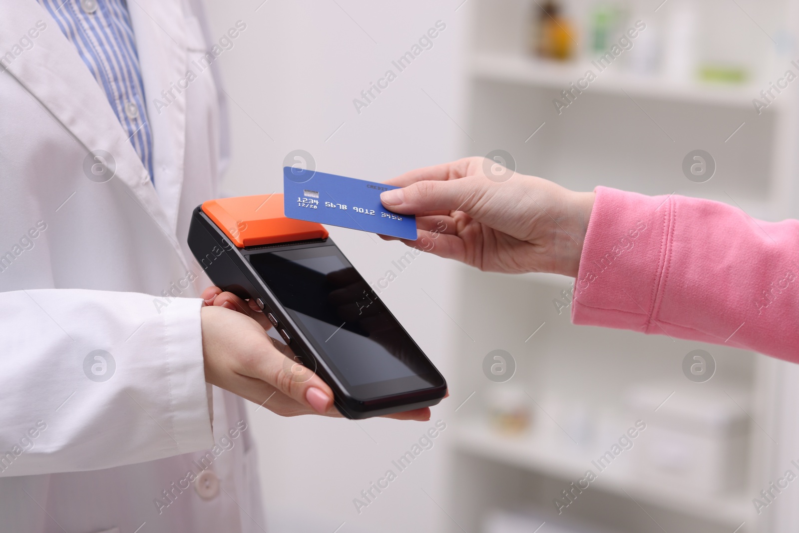 Photo of Woman paying with credit card via terminal against blurred background, closeup