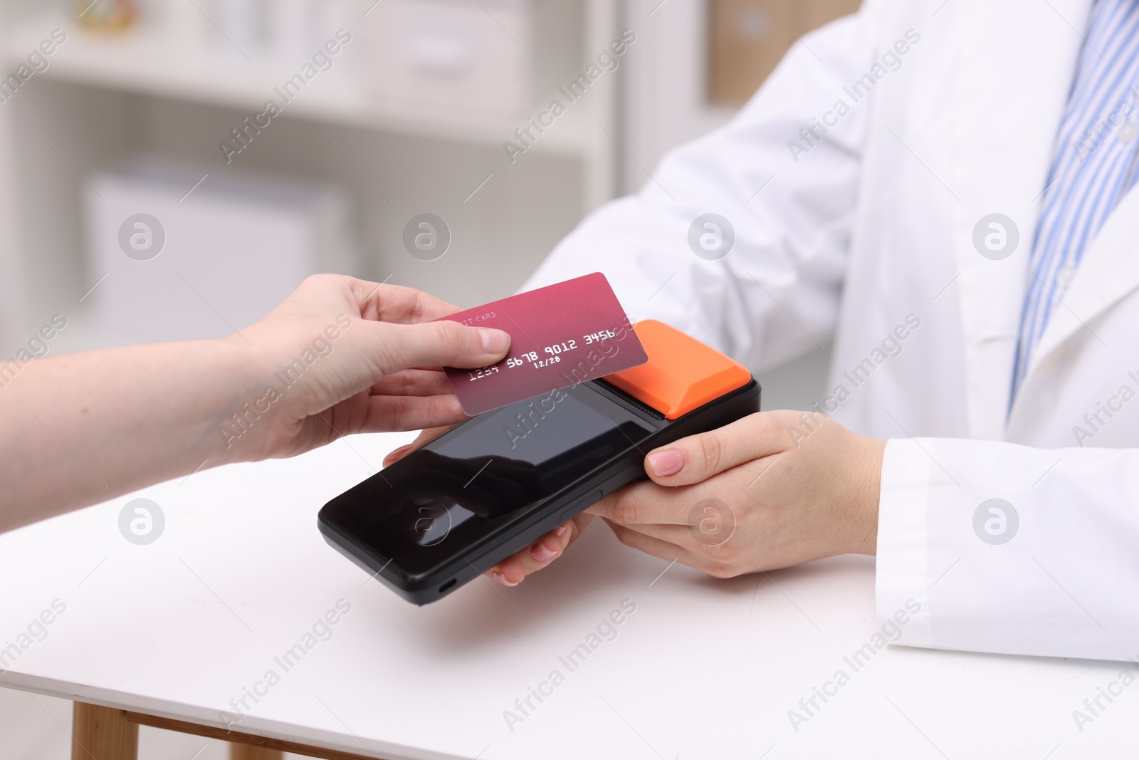 Photo of Woman paying with credit card via terminal at counter indoors, closeup