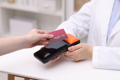 Photo of Woman paying with credit card via terminal at counter indoors, closeup