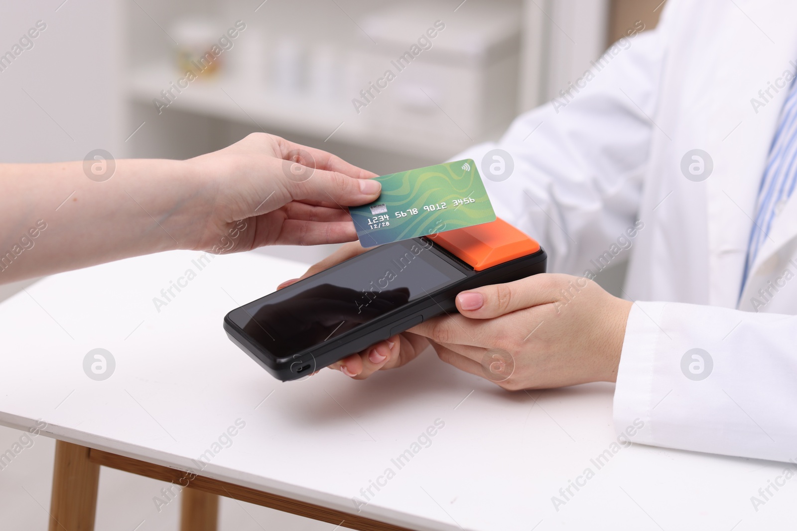 Photo of Woman paying with credit card via terminal at counter indoors, closeup