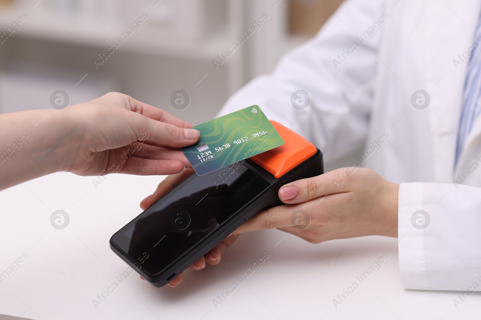 Photo of Woman paying with credit card via terminal at counter indoors, closeup