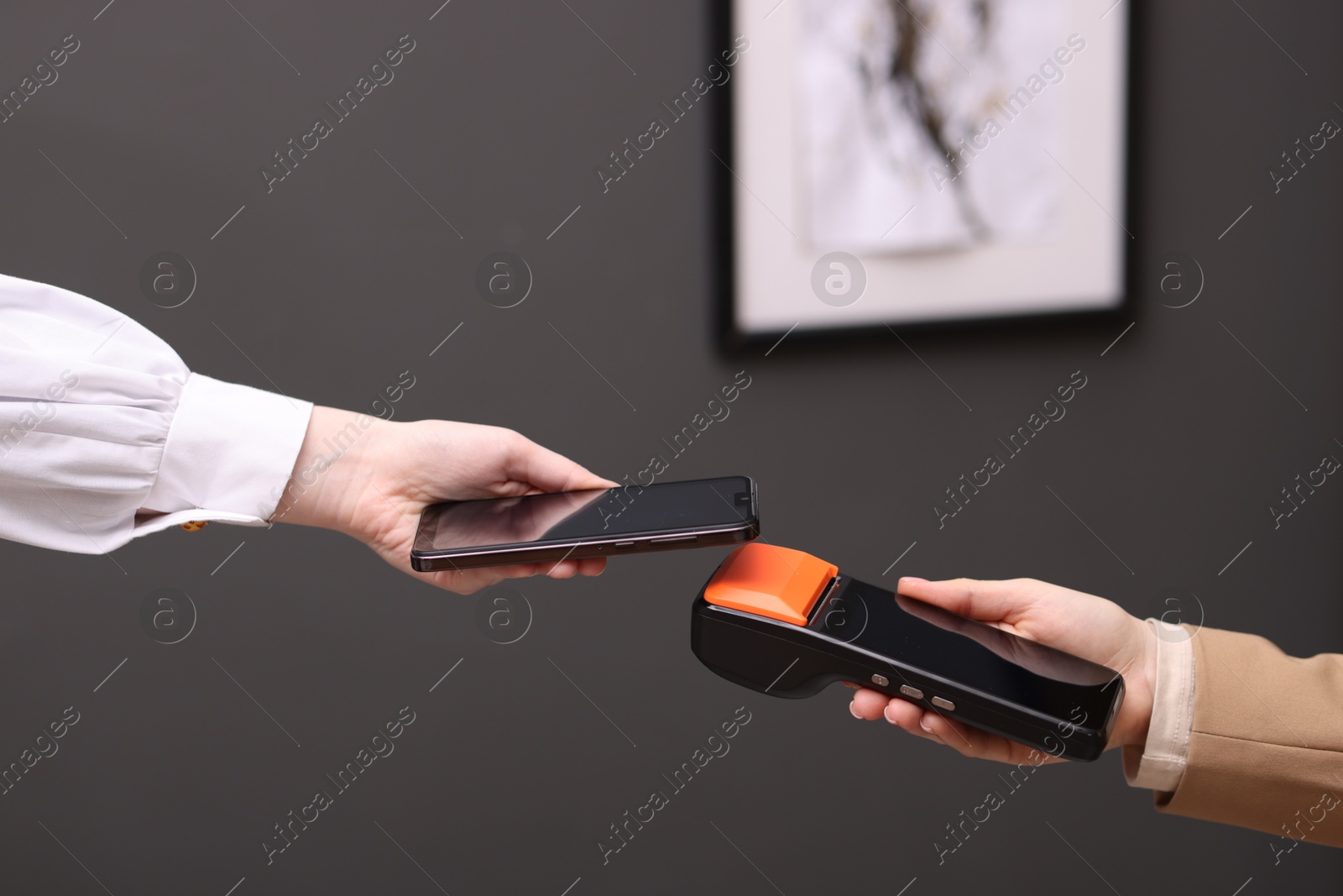 Photo of Woman paying with smartphone via terminal against blurred background, closeup