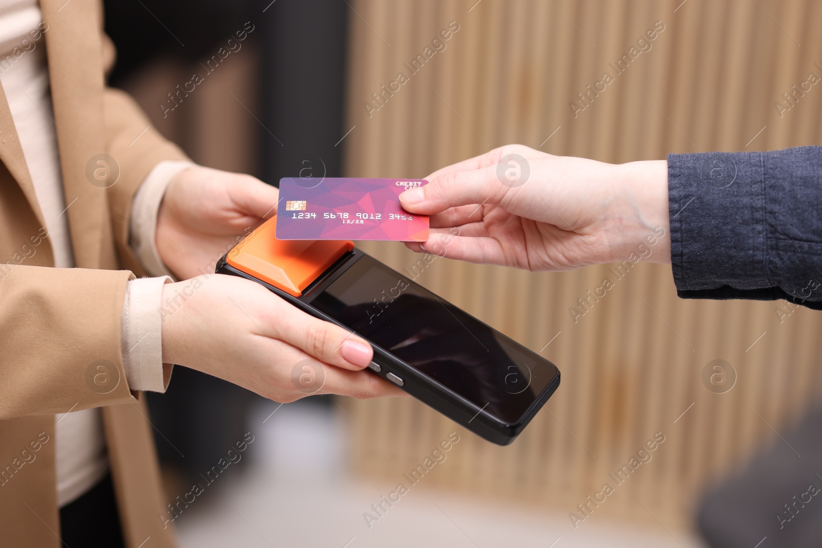 Photo of Woman paying with credit card via terminal against blurred background, closeup