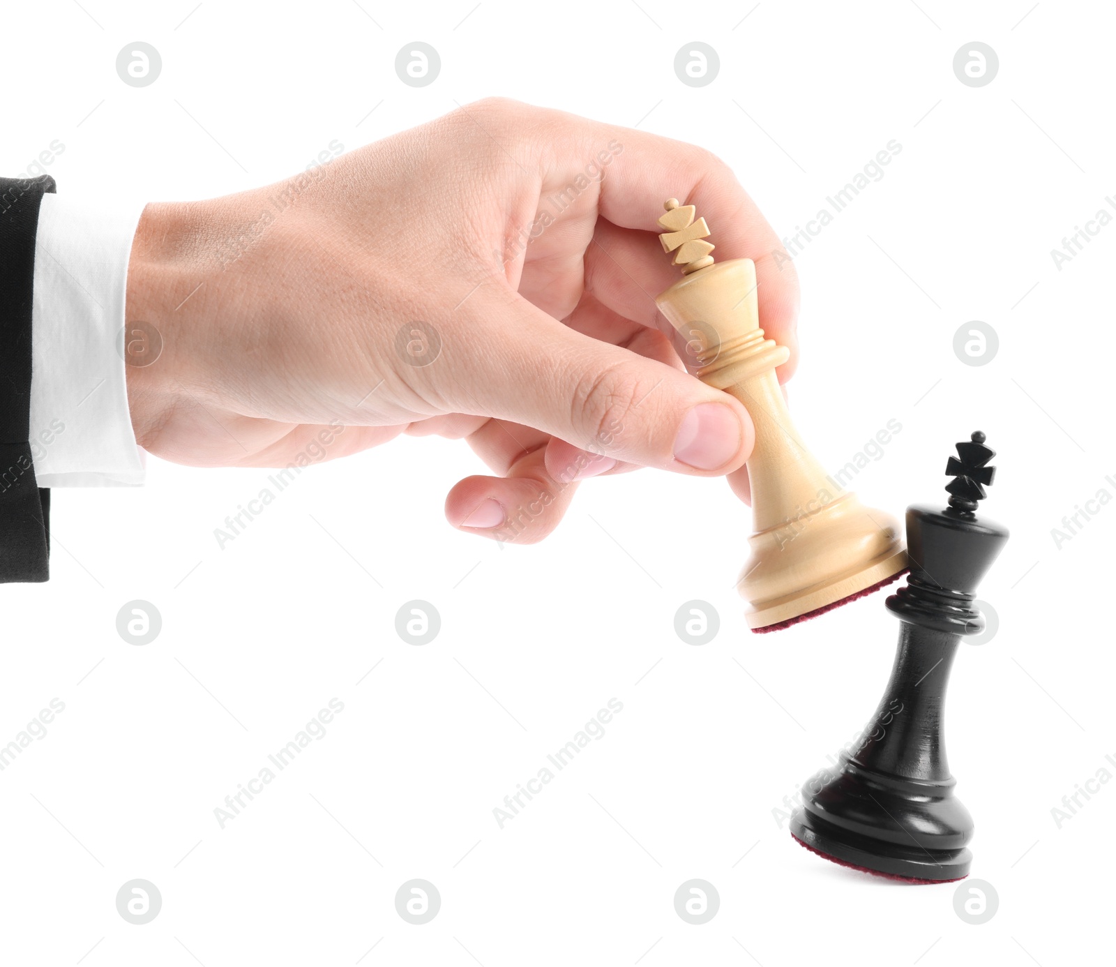 Photo of Man with white chess king knocking over black one on white background, closeup. Competition concept