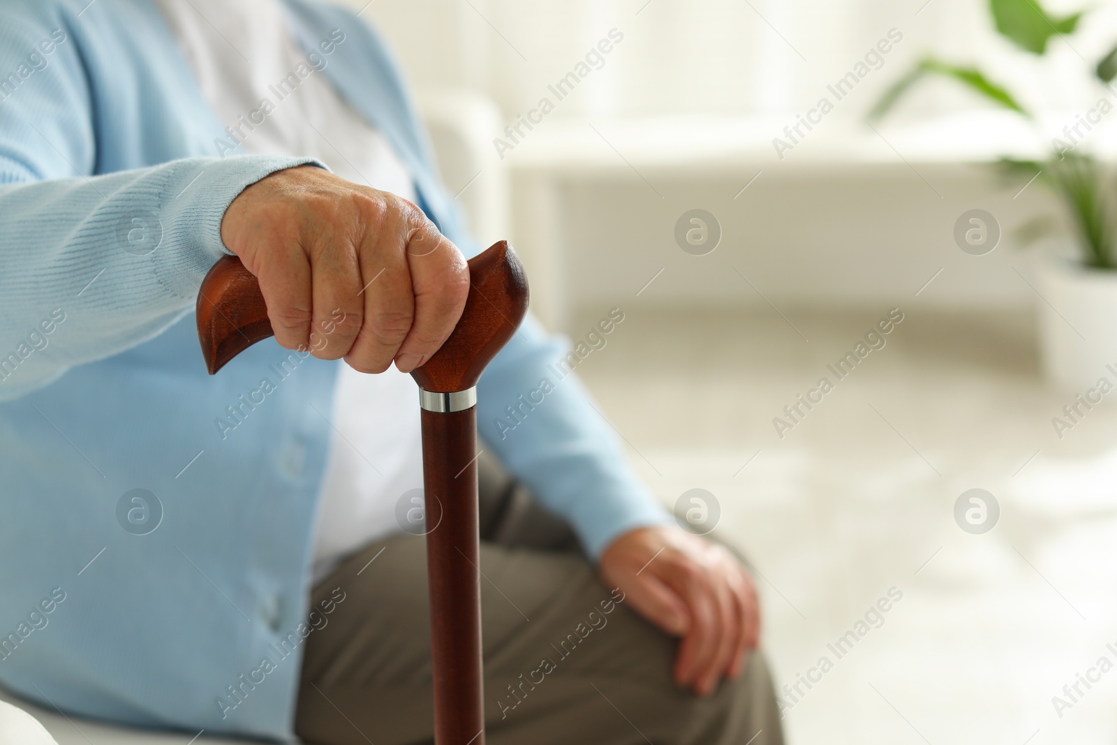 Photo of Lonely senior woman with walking cane indoors, closeup. Space for text