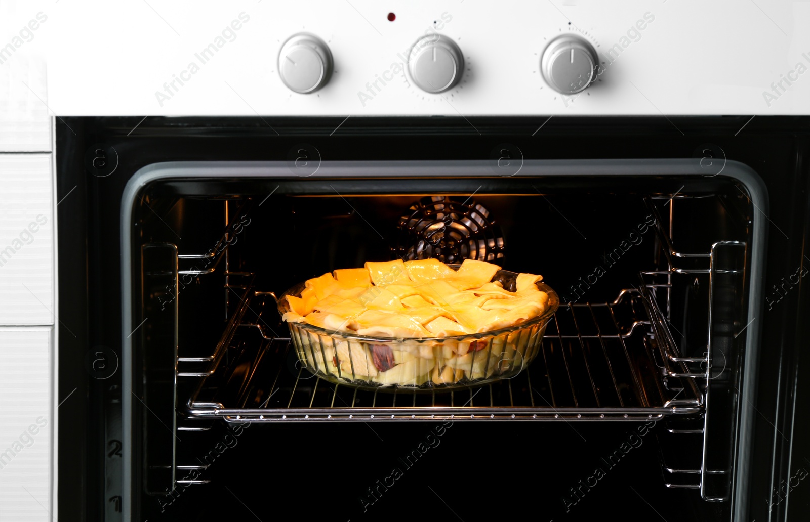 Photo of Baking dish with raw homemade apple pie in oven