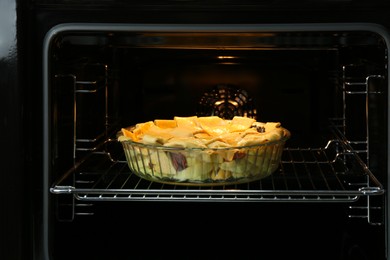 Photo of Baking dish with raw homemade apple pie in oven