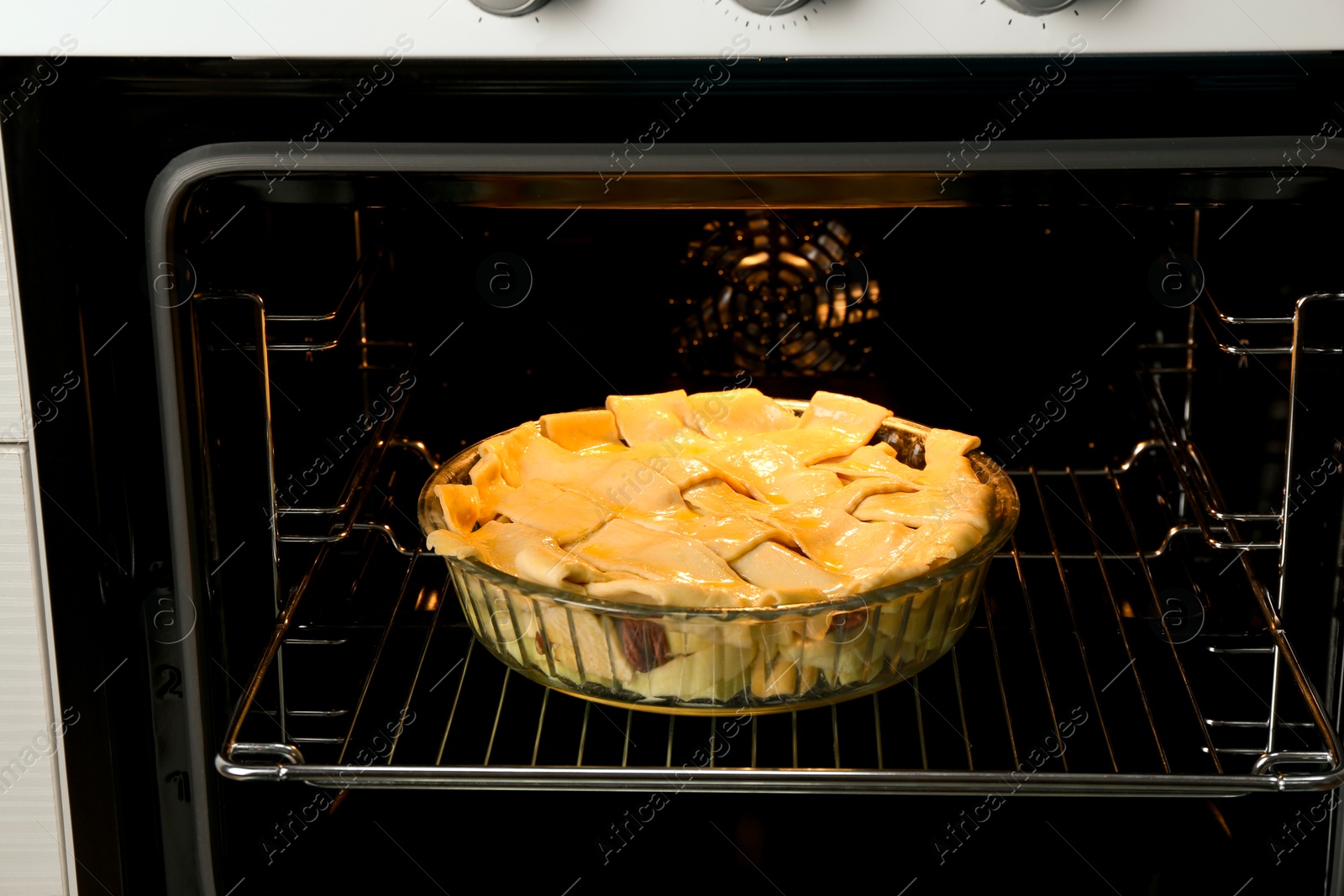 Photo of Baking dish with raw homemade apple pie in oven