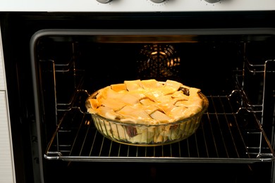 Photo of Baking dish with raw homemade apple pie in oven