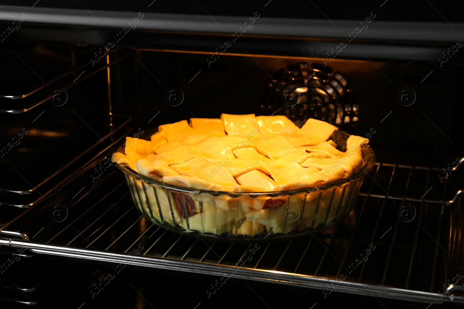 Photo of Baking dish with raw homemade apple pie in oven