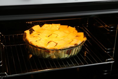 Photo of Baking dish with raw homemade apple pie in oven