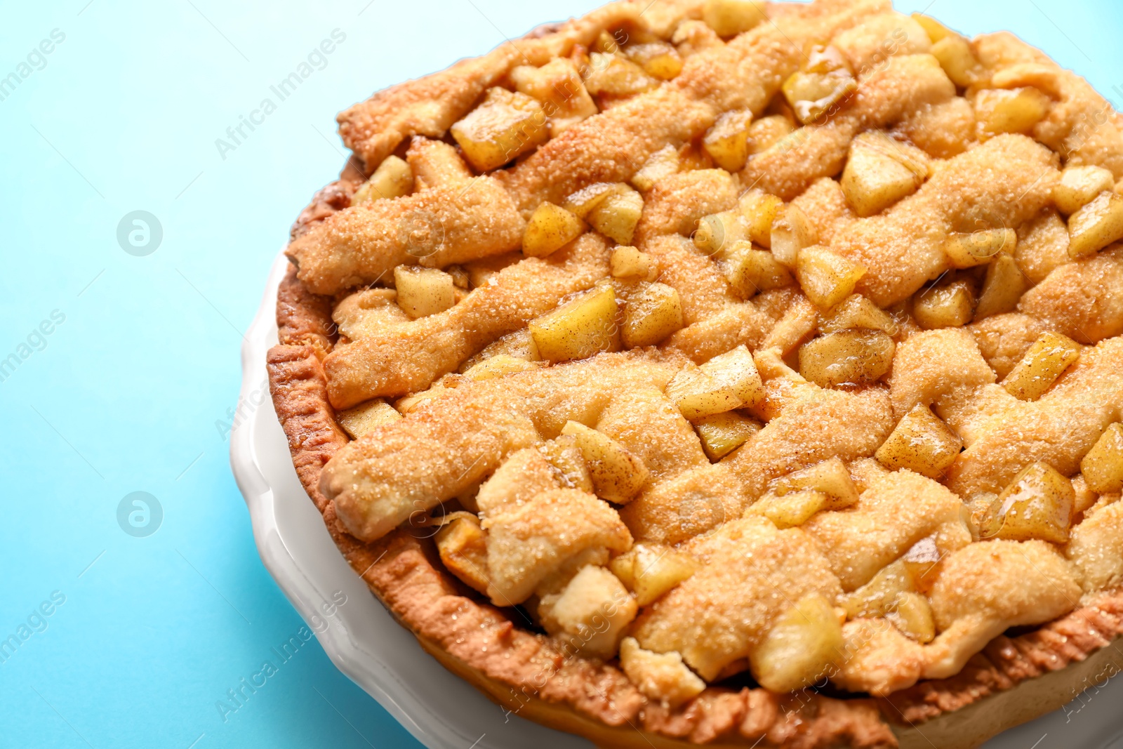 Photo of Tasty homemade apple pie on light blue background, closeup