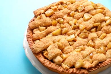 Photo of Tasty homemade apple pie on light blue background, closeup