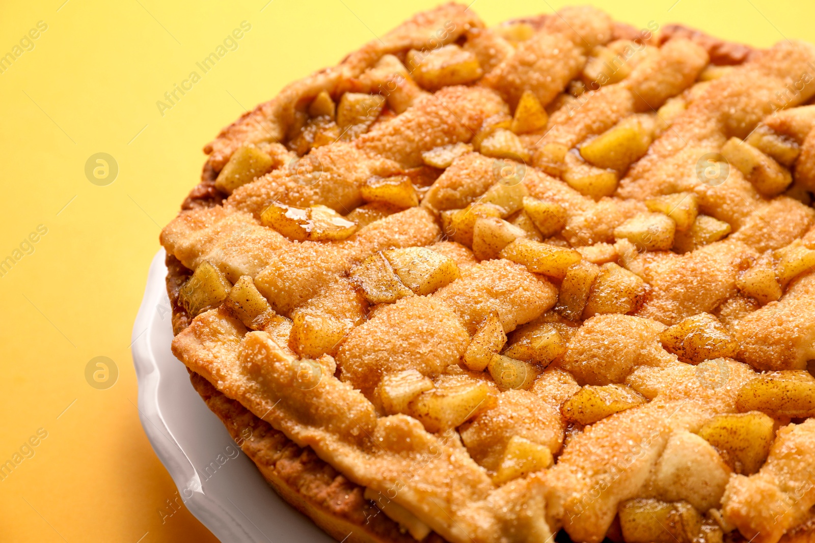 Photo of Tasty homemade apple pie on yellow background, closeup