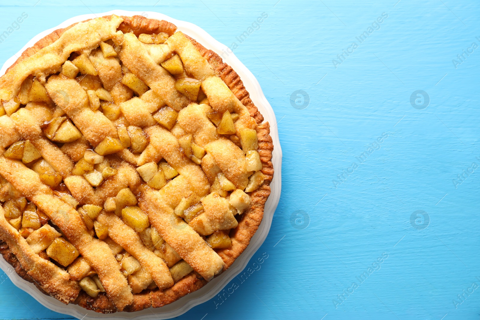 Photo of Tasty homemade apple pie on light blue wooden table, top view. Space for text