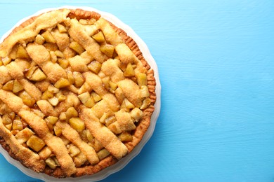 Photo of Tasty homemade apple pie on light blue wooden table, top view. Space for text