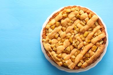 Photo of Tasty homemade apple pie on light blue wooden table, top view. Space for text