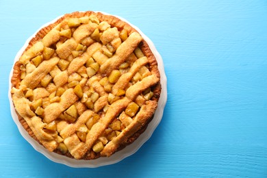 Photo of Tasty homemade apple pie on light blue wooden table, top view. Space for text