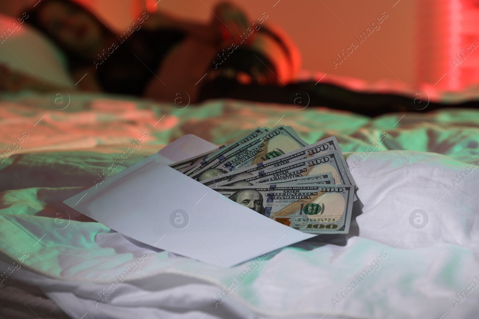 Photo of Prostitution. Woman in underwear on bed indoors, focus on dollar banknotes