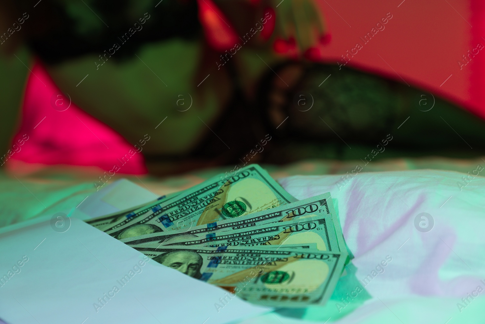 Photo of Prostitution. Woman in underwear on bed indoors, focus on dollar banknotes