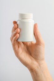 Photo of Woman holding medical bottle with pills on white background, closeup