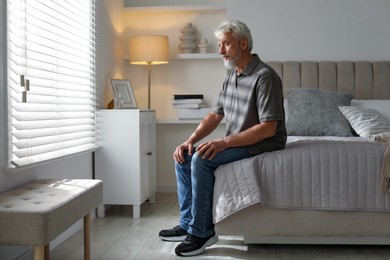 Photo of Lonely senior man sitting on bed at home