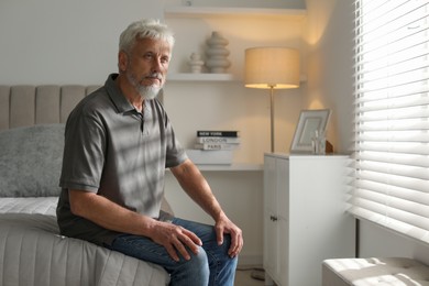 Photo of Lonely senior man sitting on bed at home