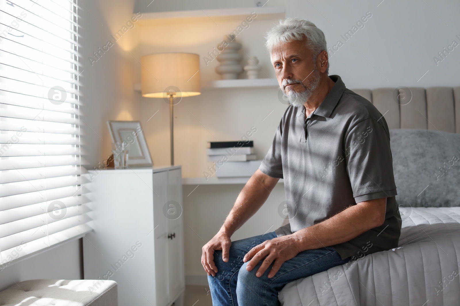 Photo of Lonely senior man sitting on bed at home