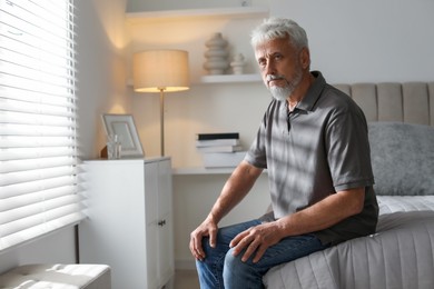 Photo of Lonely senior man sitting on bed at home