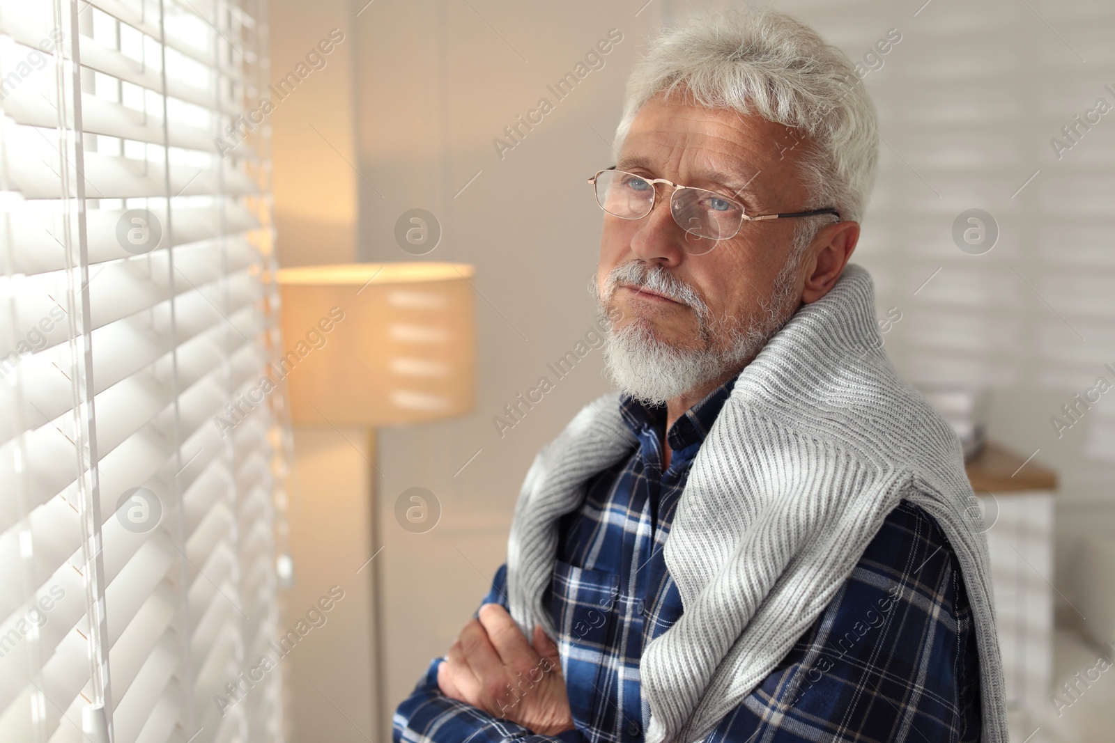 Photo of Lonely senior man looking out window indoors