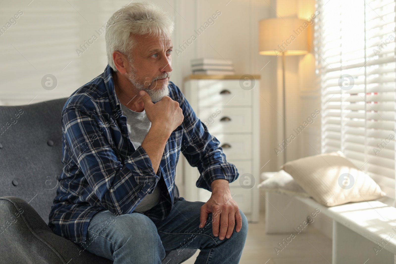 Photo of Lonely senior man sitting in armchair at home. Space for text