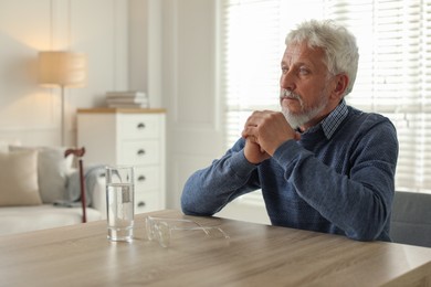 Photo of Lonely senior man sitting at table in room