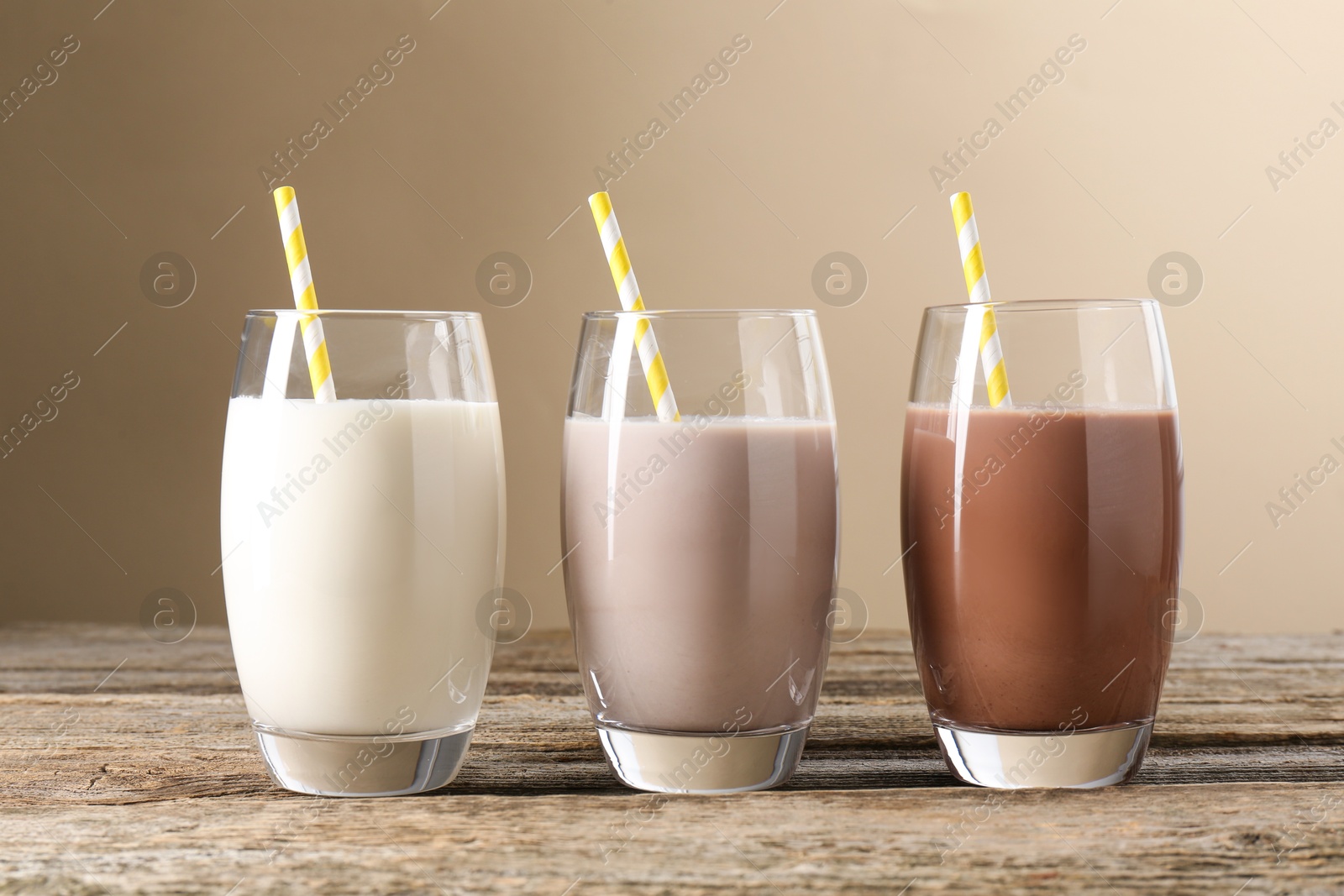 Photo of Different tasty protein cocktails in glasses on wooden table