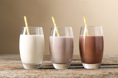 Photo of Different tasty protein cocktails in glasses on wooden table