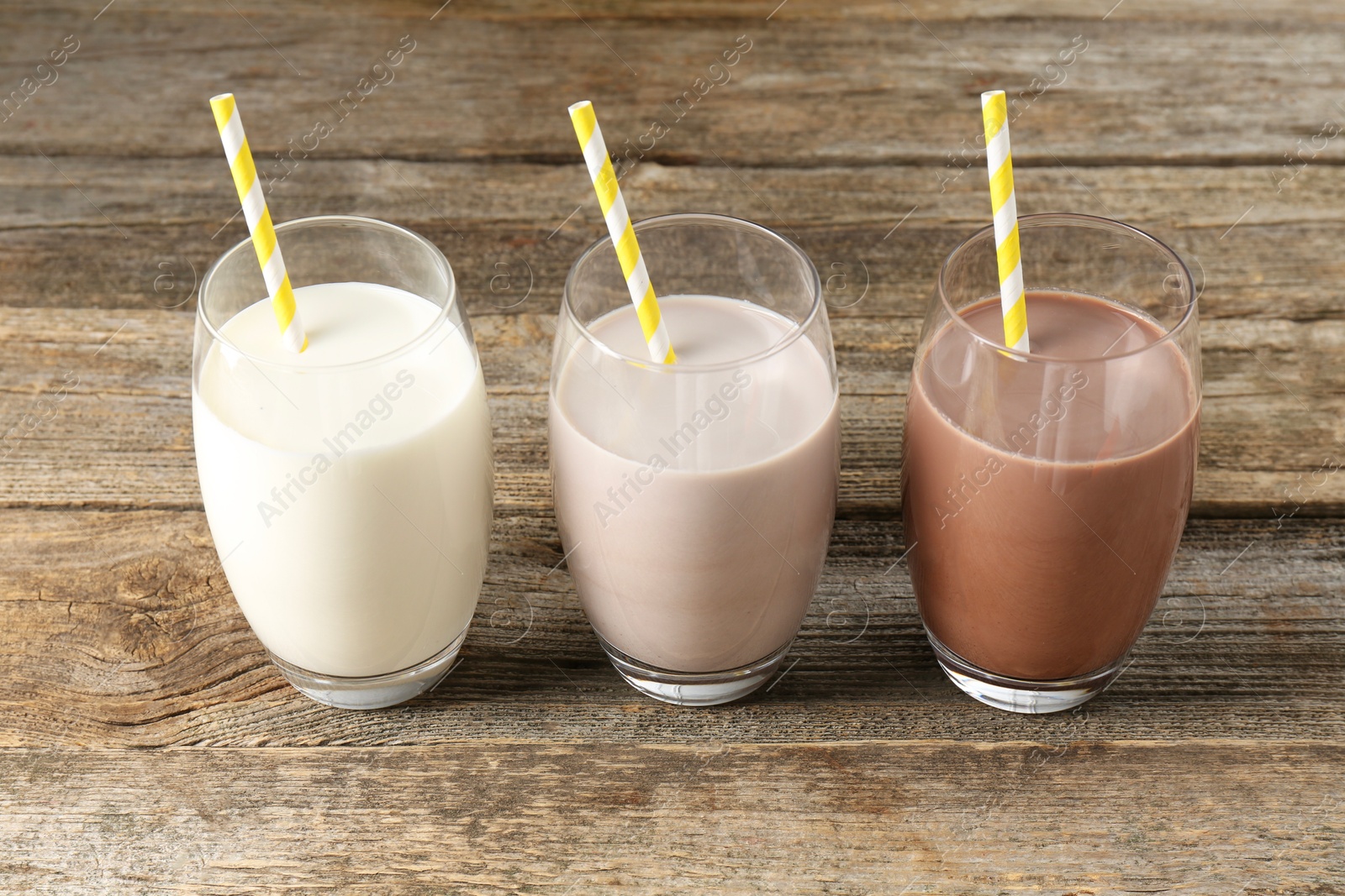 Photo of Different tasty protein cocktails in glasses on wooden table