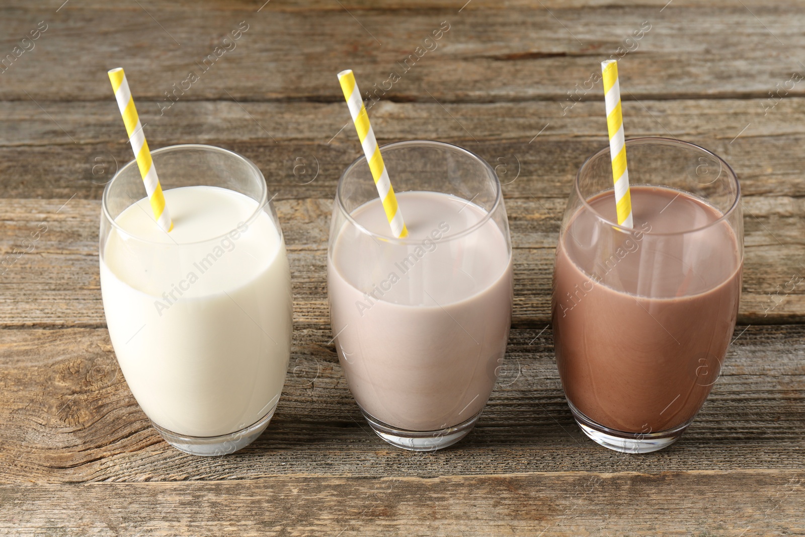 Photo of Different tasty protein cocktails in glasses on wooden table