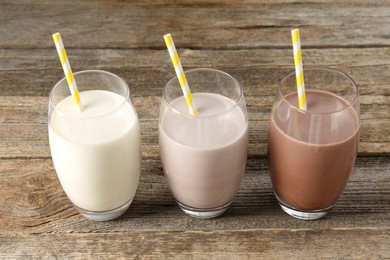 Photo of Different tasty protein cocktails in glasses on wooden table