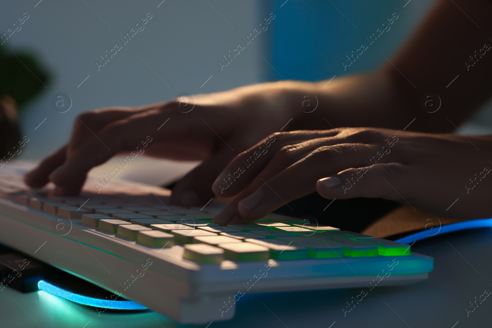 Photo of Woman using computer keyboard at white table indoors, closeup