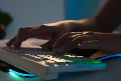 Photo of Woman using computer keyboard at white table indoors, closeup