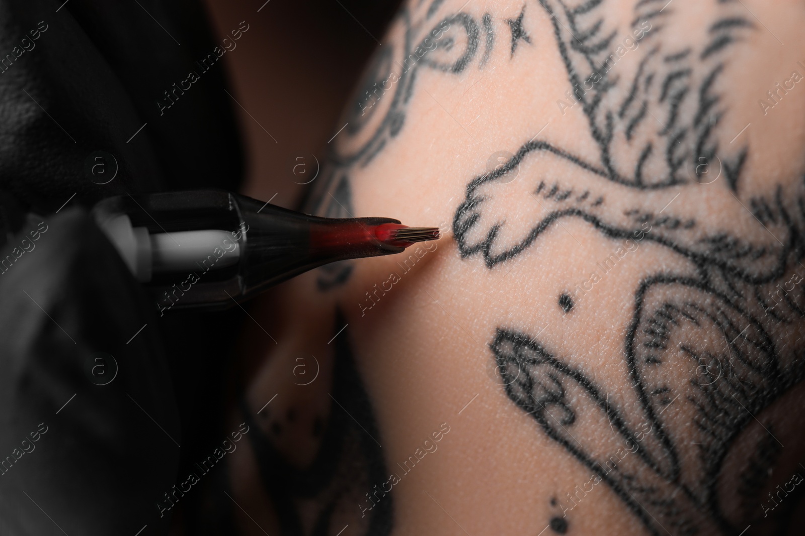 Photo of Artist in glove tattooing woman with machine, macro view