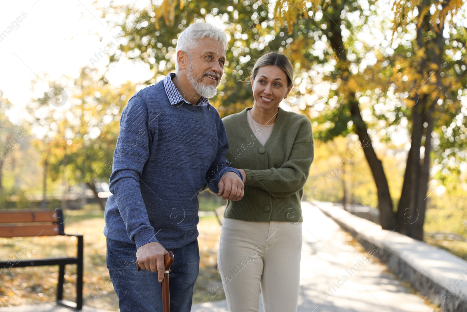 Photo of Caregiver assisting senior man in park. Home health care service