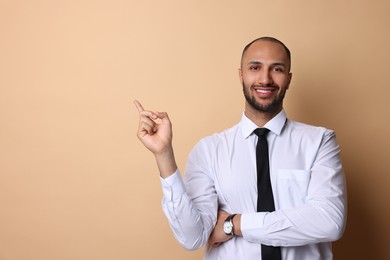 Photo of Portrait of businessman pointing at something on beige background, space for text