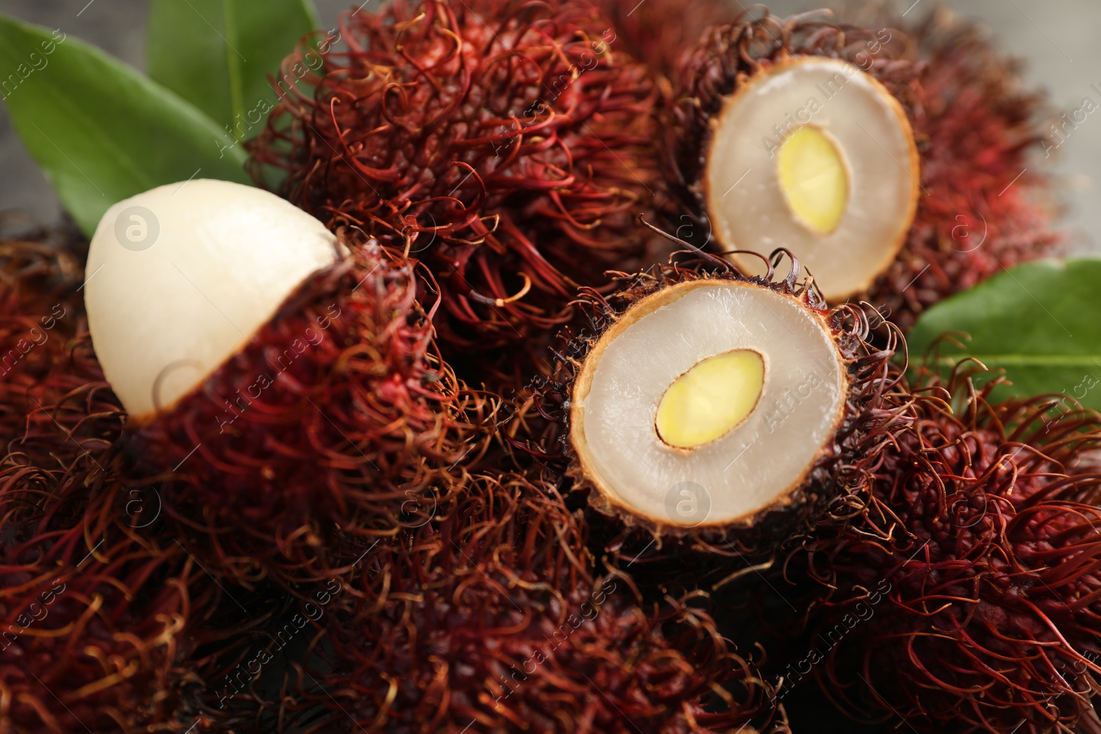 Photo of Delicious ripe rambutans and green leaves, closeup