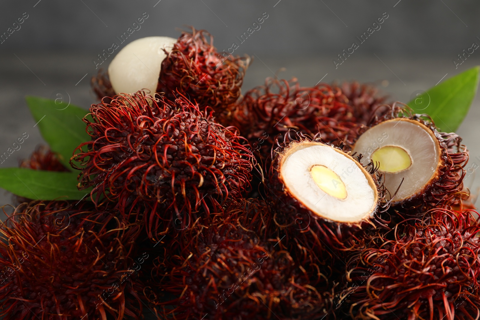 Photo of Delicious ripe rambutans and green leaves on blurred background, closeup