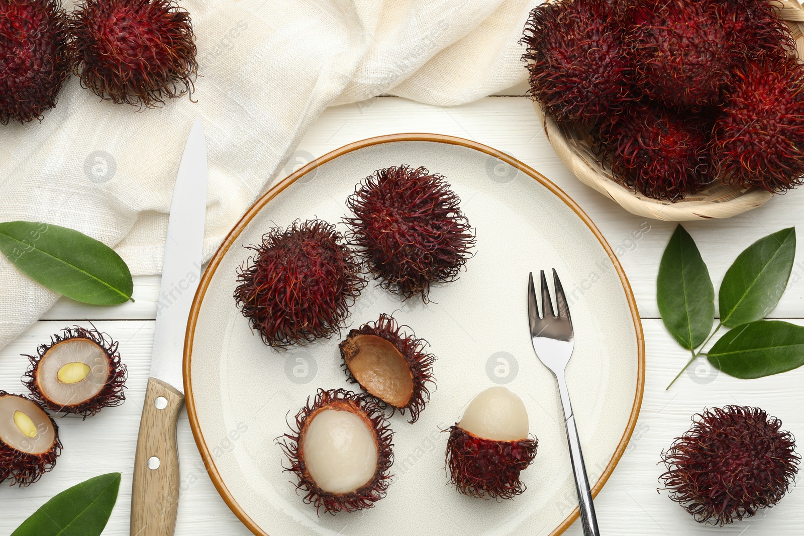 Photo of Delicious ripe rambutans served on white wooden table, flat lay