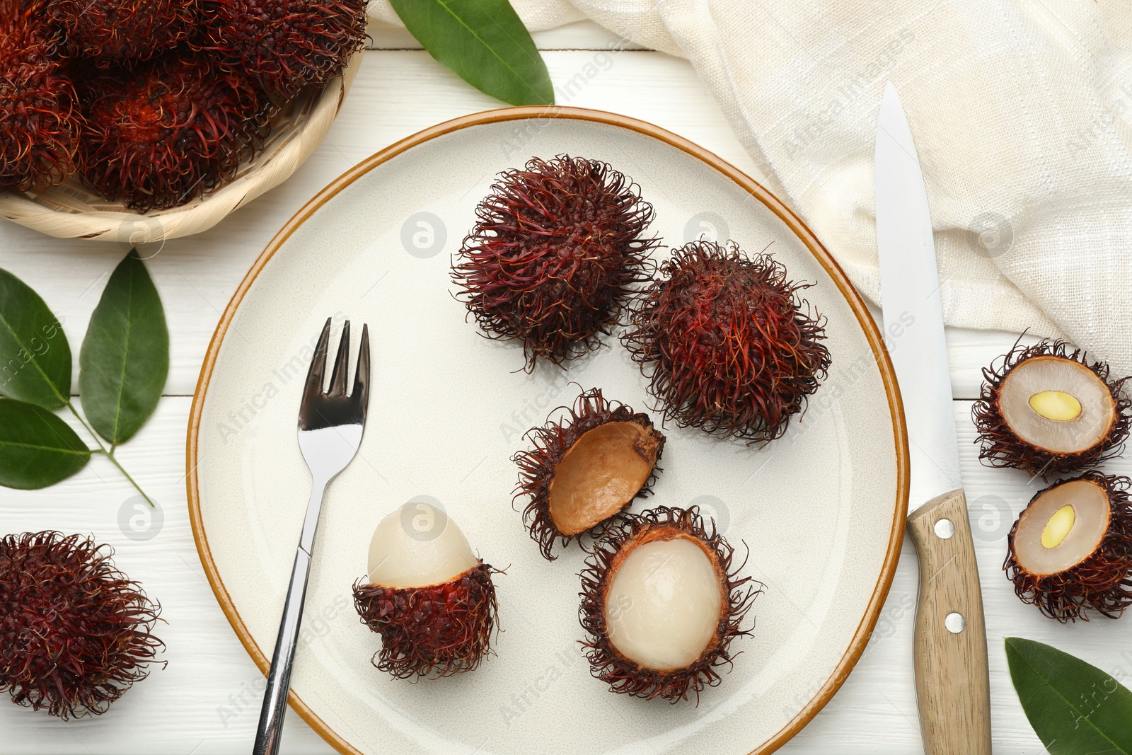 Photo of Delicious ripe rambutans served on white wooden table, flat lay