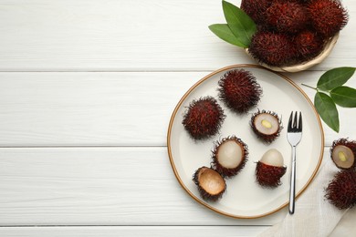 Photo of Delicious ripe rambutans served on white wooden table, flat lay. Space for text