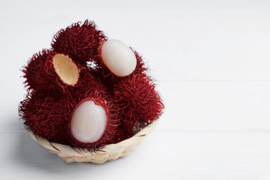 Photo of Delicious ripe rambutans on white wooden table, closeup. Space for text